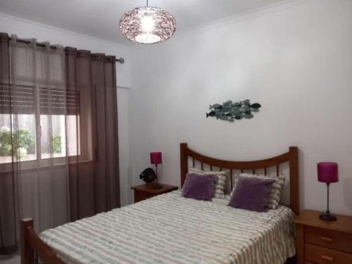 a bedroom with a bed with purple pillows and a window at BEACH house in Sesimbra