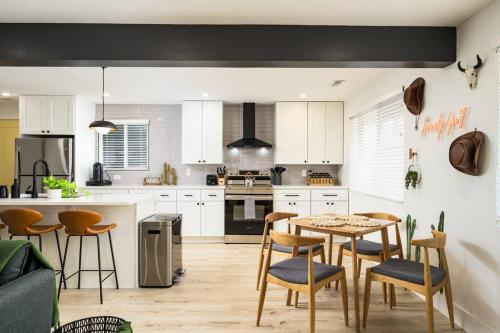 a kitchen with white cabinets and a table and chairs at Wild West Disco Haus! New Hot Tub, Patio + Gym in Denver