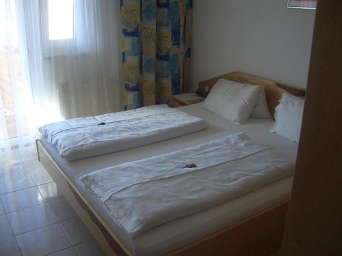two twin beds in a room with a window at Gästehaus und Weinbau Zur Wiederkehr Strudler in Podersdorf am See