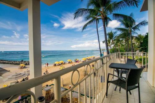 uma varanda com uma mesa e cadeiras e uma praia em Waikiki Shore by OUTRIGGER - Select Your Unit em Honolulu
