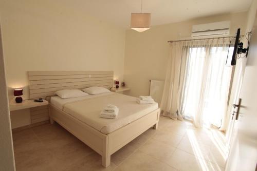 a white bedroom with a bed and a window at Asterias in Skiros