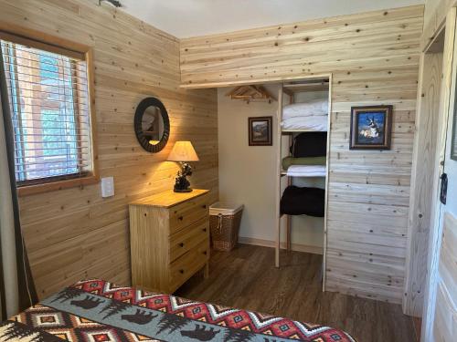 - une chambre avec des murs en bois, un lit et un miroir dans l'établissement Strawberry Patch, à Duck Creek Village
