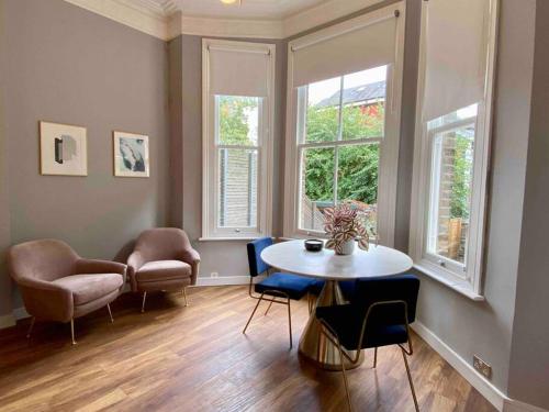 ein Wohnzimmer mit einem Tisch, Stühlen und Fenstern in der Unterkunft Stylish Studio for 2 near Regents Park n4 in London