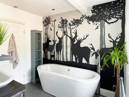 a bathroom with a white tub and deer mural on the wall at Keepsake View in Two Dales