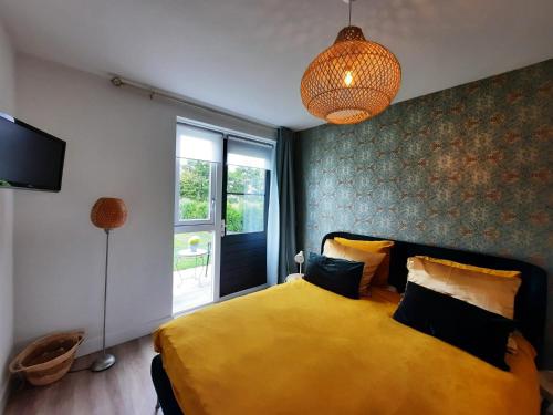 a bedroom with a yellow bed and a window at Studio Flevo Batavia in Lelystad