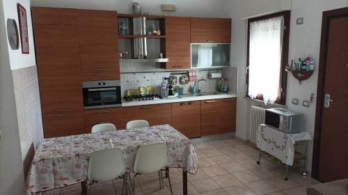 una cocina con mesa y sillas y una cocina con armarios de madera. en Casa Emily, en Fano