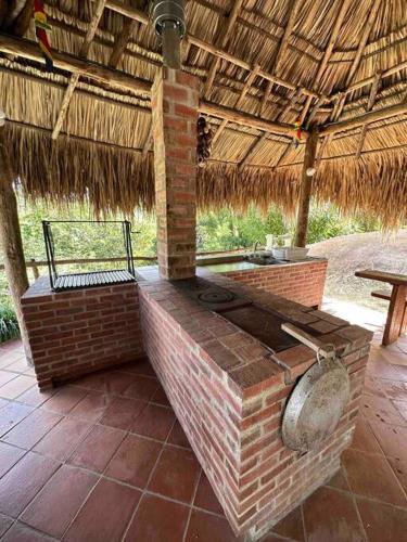 an outdoor brick oven with a straw roof at increible casa de campo con piscina y jacuzzi! in Támesis