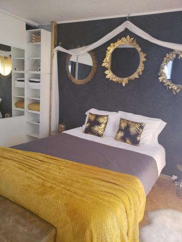 um quarto com uma cama grande e espelhos na parede em Miss G'Ainguette em Guéreins