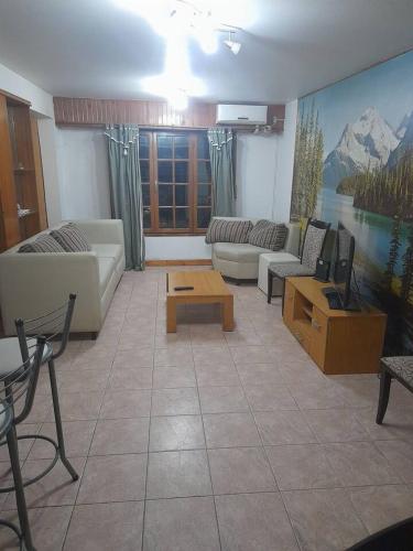 sala de estar con sofás, mesa y TV en Patagones Alojamiento en Carmen de Patagones