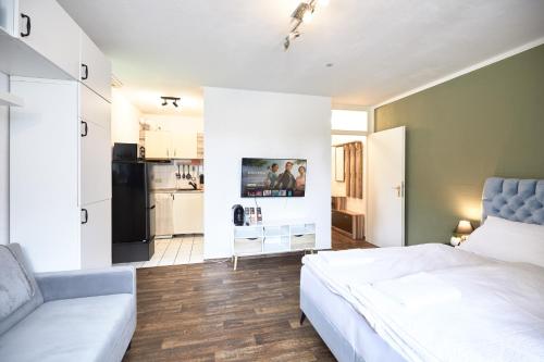 a bedroom with a bed and a couch and a kitchen at Stilvolles Ruhiges Studio - PARKPLATZ, WIFI, TV EM-APARTMENTS DEUTSCHLAND in Bielefeld