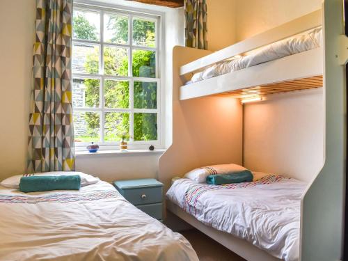 a bedroom with two bunk beds and a window at The Stables in Sedbergh