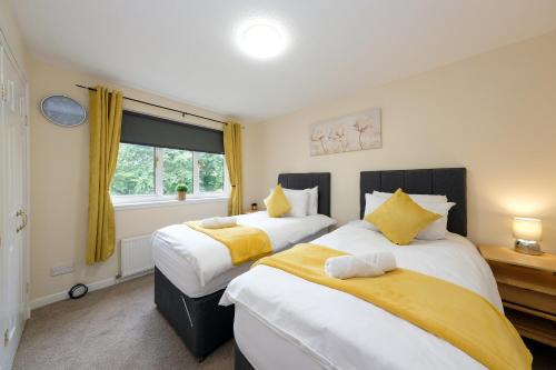 two beds in a bedroom with yellow and white at Pure Apartments Commuter- Dunfermline South in Fife