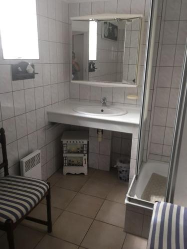 une salle de bain avec un lavabo, un miroir et une chaise dans l'établissement LE clos do ré, à Sainte-Marie de Ré