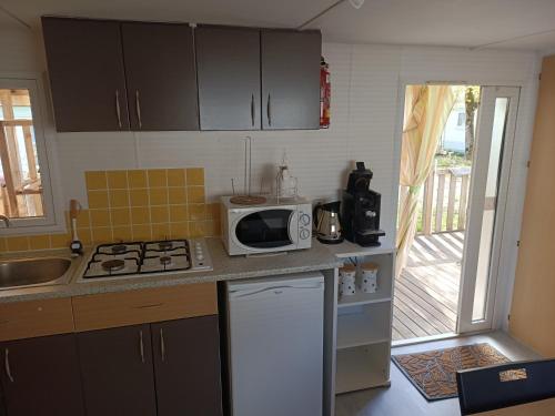une cuisine avec un micro-ondes et une cuisinière four supérieur dans l'établissement Mobile Home, à Avrillé