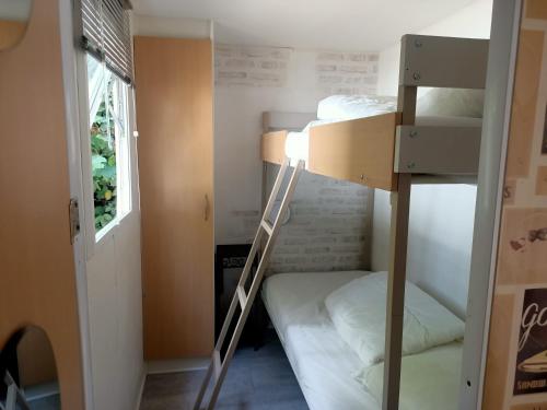 a dorm room with two bunk beds and a window at Mobile Home in Avrillé