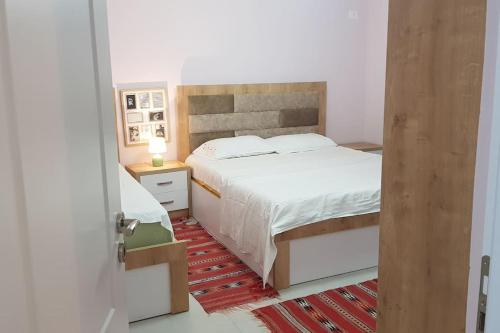 um quarto com uma cama branca e um tapete vermelho em Shengjergj shtepi pushimi em Tirana