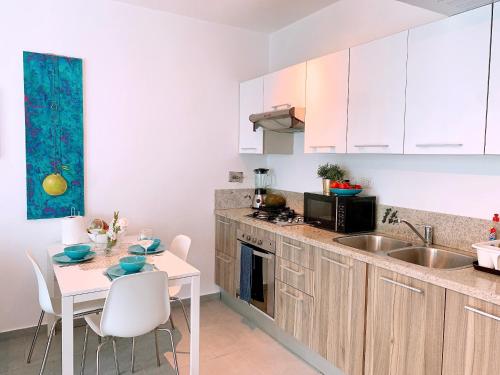 a kitchen with white cabinets and a table and a sink at Apartment in Estrella, Dominicus-Bayahibe in La Laguna