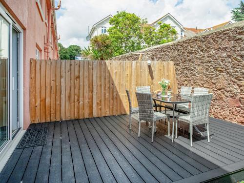a patio with a table and chairs on a wooden deck at Garden Apartment - Uk44654 in Paignton