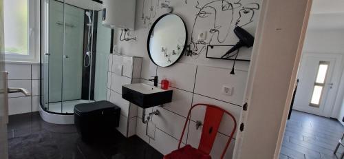ein Bad mit einem Waschbecken und einem Wandspiegel in der Unterkunft Apartment Stella Danica in Čatež ob Savi