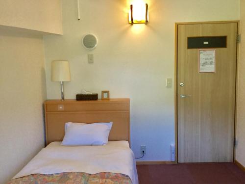 ein Schlafzimmer mit einem Bett, einer Lampe und einer Tür in der Unterkunft Wakkanai - House / Vacation STAY 4156 in Wakkanai