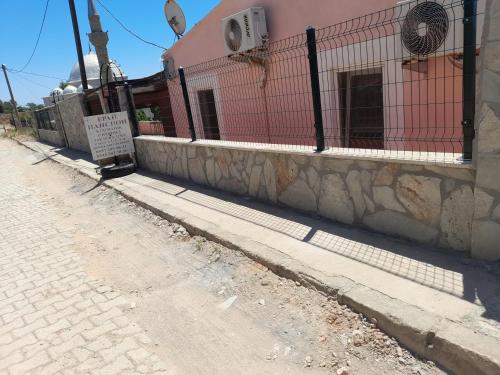 una calle vacía al lado de un edificio con una valla en ERAY PANSİYON, en Gokceada Town