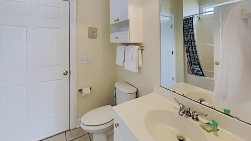 a white bathroom with a toilet and a sink at Golf and Beach Getaway Relaxation at its Finest in Pawleys Island