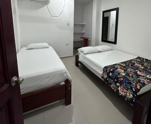 1 dormitorio con 2 camas y espejo en Hotel Casa Evan, en Mompox