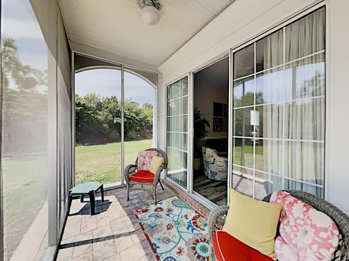 a screened porch with chairs and a table at Retreat to Coastal Elegance: Golf and Beach Access in Pawleys Island