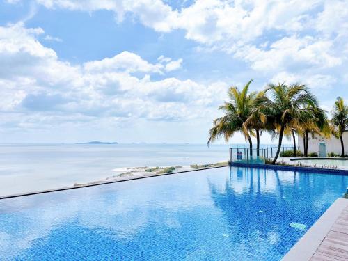 a swimming pool with palm trees and the ocean at Silverscape - Luxury 3-4BR with Bathtub I 6-11pax I Infinity Pool I JonkerSt - Managed by Alviv Homestay in Melaka