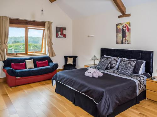 a bedroom with a bed and a couch and a window at Blackberry Barn in Tortworth