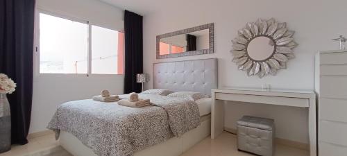 a white bedroom with a bed and a mirror at Balcon Roque del Conde in Adeje