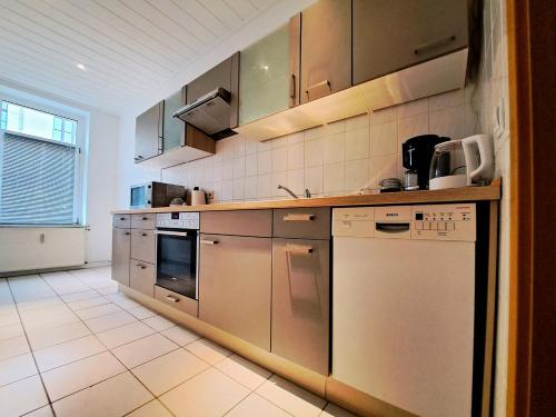eine Küche mit Küchengeräten aus Edelstahl und Fliesenboden in der Unterkunft Apartment Hotel Adler Leipzig in Leipzig