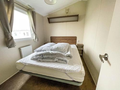 a bedroom with a bed with white sheets and a window at Superb 8 Berth Caravan For Hire At A Great Holiday Park In Norfolk Ref 50007a in Great Yarmouth