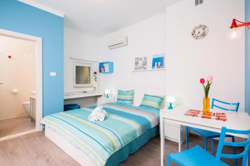 Split Dreams Apartments في سبليت: غرفة نوم زرقاء مع سرير ومكتب وطاولة