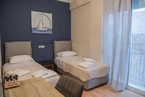 a room with two beds and a table and a sailboat on the wall at Urban Oasis, Stylish Short Stay Apartment in Piraeus Center in Piraeus