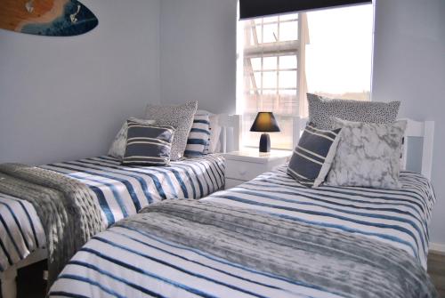 three beds in a room with blue and white stripes at 201 Hexrivier in Hartenbos