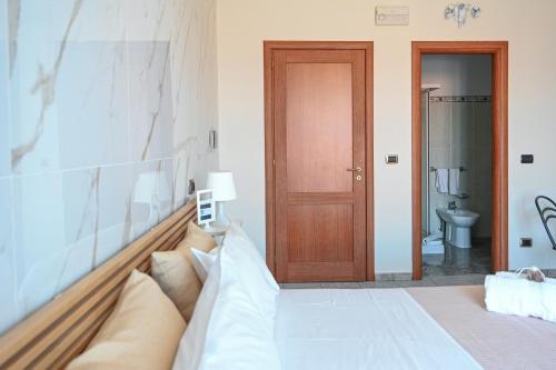 - une chambre avec un grand lit et une porte en bois dans l'établissement Il Porticciolo, à Scilla