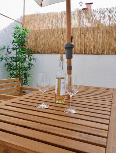 a bottle of wine and two glasses on a wooden table at Caparica Coast Townhouse Apartments in Charneca
