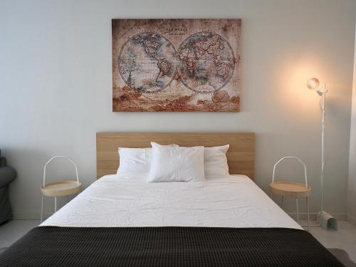 夏內卡的住宿－Caparica Coast Townhouse Apartments，卧室配有一张床,墙上挂有绘画作品