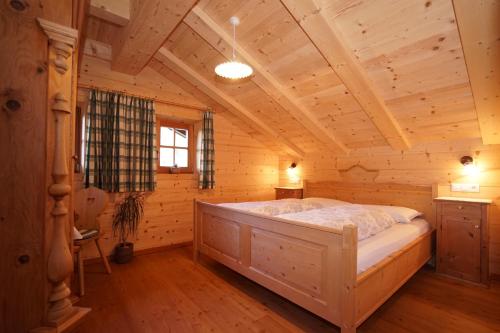 a bedroom with a bed in a log cabin at Unterhabererhof in Santa Maddalena in Casies