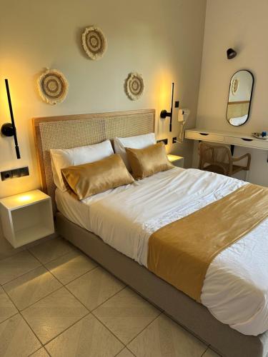 1 dormitorio con 1 cama grande con sábanas blancas y almohadas de oro en Electra Studios, en Palaiochóra