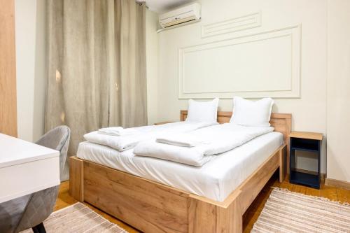 a bedroom with a bed with white sheets at ApartPro Apartments, Veliko Tarnovo in Veliko Tŭrnovo
