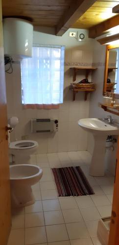 a bathroom with two toilets and a sink and a window at Casetta con camino in La Magdeleine