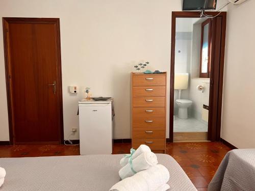een slaapkamer met een bed, een dressoir en een badkamer bij Celeste Rooms in San Vito lo Capo