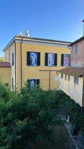 a building with faces painted on the side of it at Orizzonti Toscani new apartment with view and pool in Laiatico