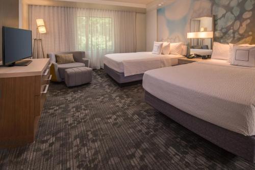 a hotel room with two beds and a flat screen tv at Courtyard by Marriott Hershey Chocolate Avenue in Hershey