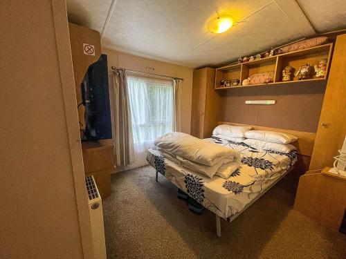 a small bedroom with two beds and a window at Lovely 6 Berth Caravan At Oaklands Holiday Park Ref 39031cw in Clacton-on-Sea