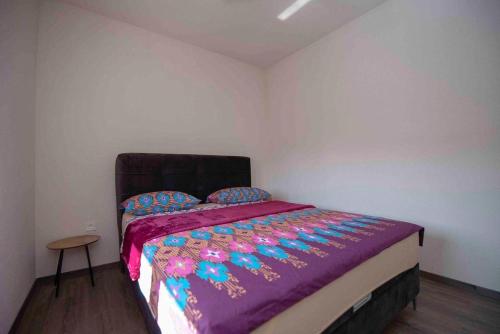 a bedroom with a bed with a purple comforter at Apartmani Berdovic in Trebinje