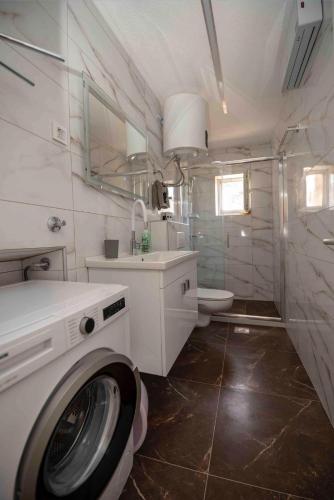 a white bathroom with a washing machine in it at Apartmani Berdovic in Trebinje