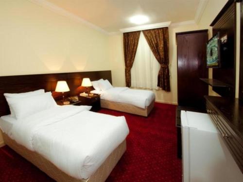 a hotel room with two beds and a red carpet at Royal Almashaer in Makkah